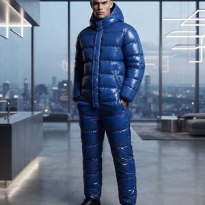 May include: A glossy, royal blue puffer jumpsuit featuring a high-neck hooded jacket with a front zipper closure and matching insulated trousers. The garment has a shiny, reflective finish and horizontal quilted stitching throughout the entire piece.