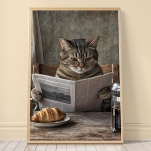 Può includere: Un gatto soriano marrone con occhiali tondi con montatura in metallo siede a un tavolo di legno leggendo un giornale. Un cornetto dorato riposa su un piattino accanto a una caffettiera a stantuffo in vetro. Il gatto ha strisce scure.