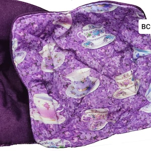 May include: Purple quilted hot pad with a floral pattern of teacups and saucers on a purple background. The back of the hot pad is solid purple. The text "BC-36" is printed in white on the upper right corner of the hot pad.