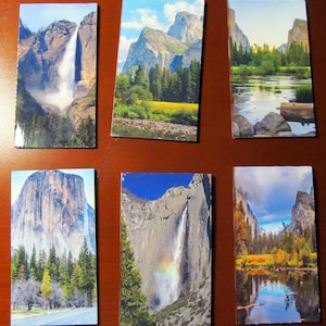 May include: A set of six postcards featuring scenic views of Yosemite National Park. The postcards showcase various landscapes, including waterfalls, mountains, and forests.