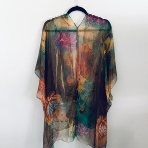 K&ouml;nnte beinhalten: Ein durchsichtiges Kimono mit floralem Muster in Braun, Gr&uuml;n und Lila mit V-Ausschnitt.