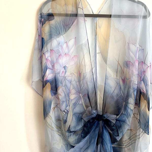 Peut inclure: Une écharpe en soie bleu et blanc transparente avec un imprimé floral de fleurs et de feuilles de lotus. L'écharpe est nouée au centre.