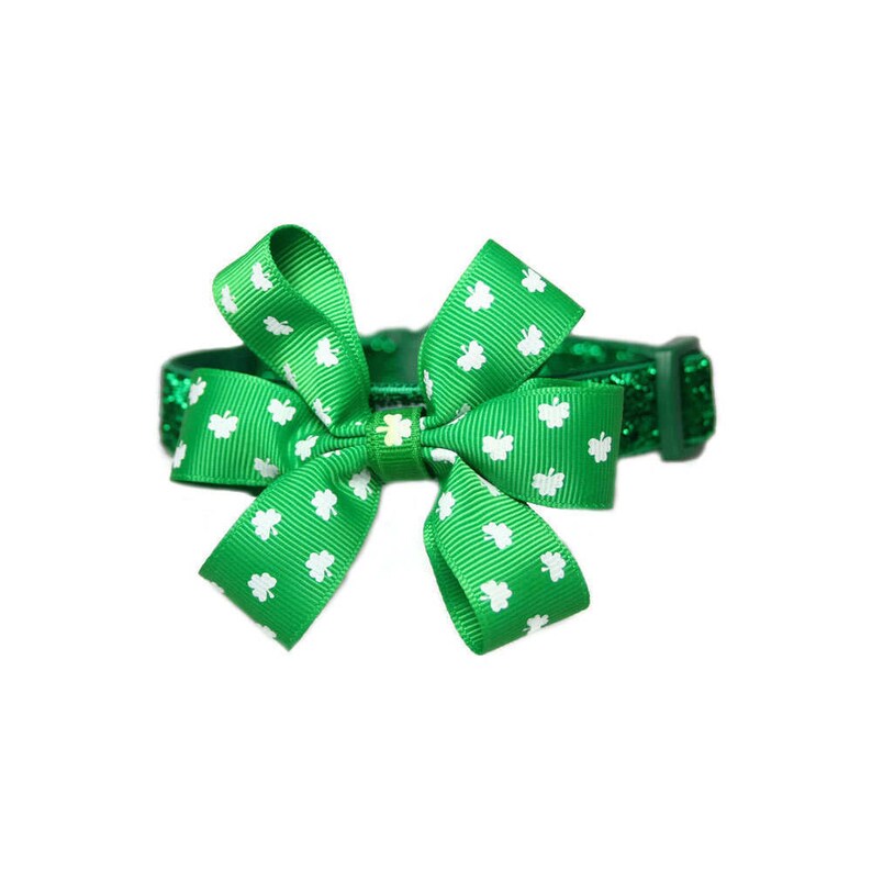 May include: Green glitter pet collar with a green shamrock patterned bow. The bow is tied in a knot and has white shamrocks.