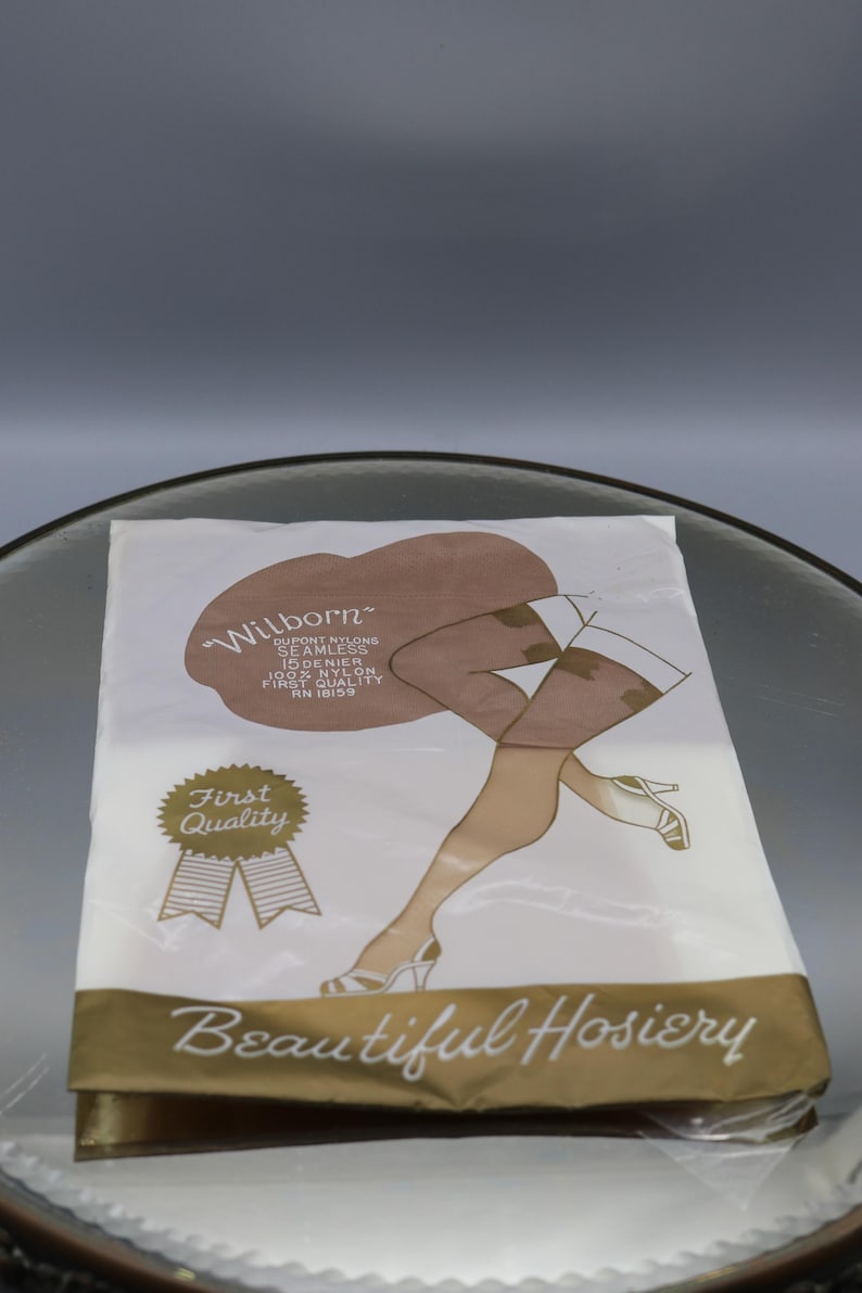Puede incluir: Un paquete de medias de la marca "Wilborn". El embalaje presenta una ilustraci&oacute;n de piernas de mujer con medias con un estampado floral. El texto "Beautiful Hosiery" se muestra en la parte inferior del paquete.