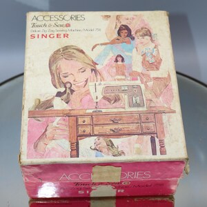 May include: A vintage Singer Touch & Sew zig zag sewing machine in a pink and white box with a picture of a woman sewing. The box has the text "Accessories Touch & Sew Deluxe Zig Zag Sewing Machine/Model 758 SINGER" printed on it.