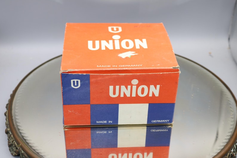 K&ouml;nnte beinhalten: Eine rote und blaue Schachtel mit dem Wort "UNION" in wei&szlig;en Buchstaben darauf. Die Schachtel ist in Deutschland hergestellt und hat ein kleines "U"-Logo an der Seite.