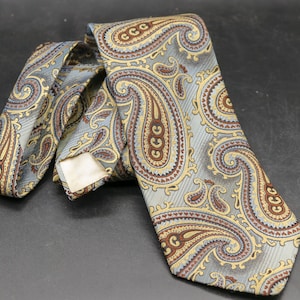 May include: A grey paisley patterned necktie with brown and gold accents.