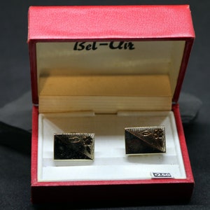 May include: A red box with a white interior and the words "Bel-Air" printed on the lid. The box contains two gold cufflinks with a floral design. The price tag reads "$2.50".