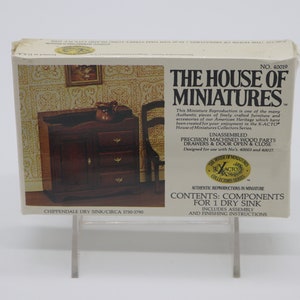 May include: A box for a miniature dry sink kit, featuring a photo of the assembled model. The box is white with black text and a red and gold logo. The text on the box reads "The House of Miniatures" and "Chippendale Dry Sink/Circa 1756-1790".