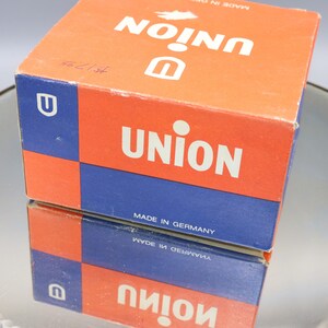 K&ouml;nnte beinhalten: Eine rote und blaue Schachtel mit dem Wort "UNION" in wei&szlig;en Buchstaben darauf gedruckt. Die Schachtel ist in Deutschland hergestellt.