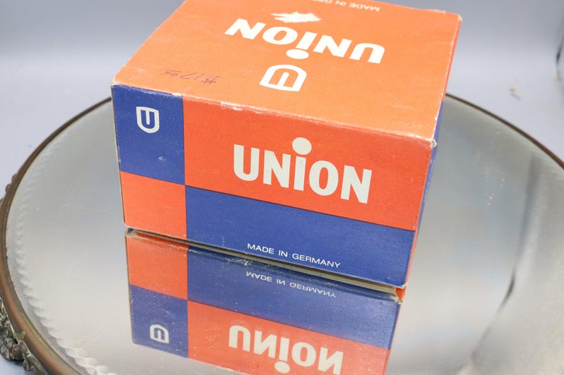 K&ouml;nnte beinhalten: Eine rote und blaue Schachtel mit dem Wort "UNION" in wei&szlig;en Buchstaben darauf gedruckt. Die Schachtel ist in Deutschland hergestellt.