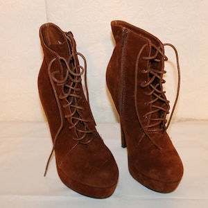 Puede incluir: Un par de botines de ante marrón con cordones y tacones altos.