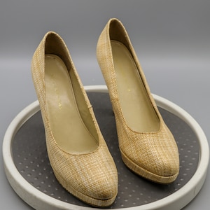 May include: A pair of beige woven high-heeled shoes. The shoes have a woven texture and a pointed toe.