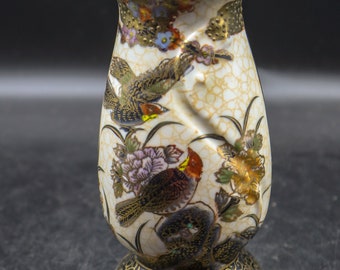 May include: A white ceramic salt shaker with a black and gold base. The shaker is decorated with a floral pattern and birds in shades of brown, red, yellow, and blue.