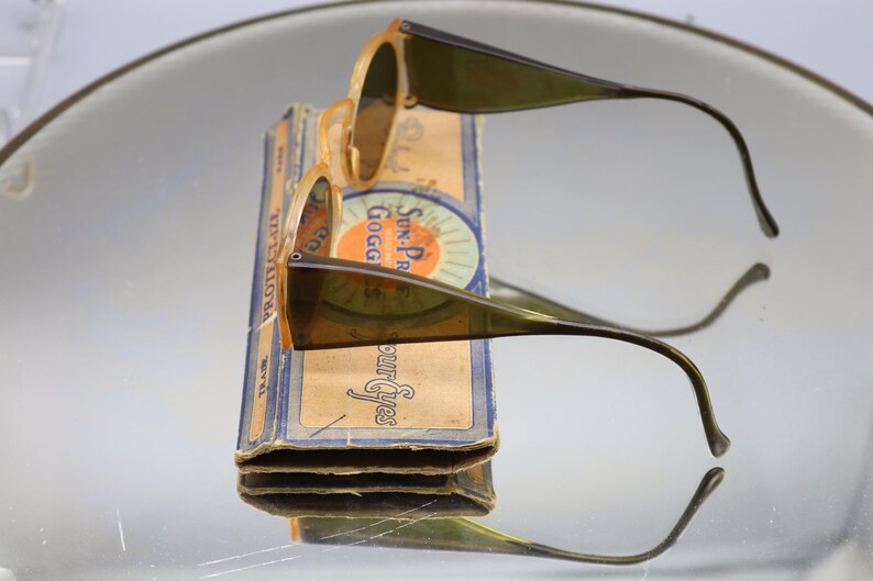 Op de afbeelding: Een witte keramische mok met een zwart handvat en de tekst "But First, Coffee" in een zwarte, vette letter. De mok staat op een wit oppervlak. De mok is ongeveer 10 cm hoog.