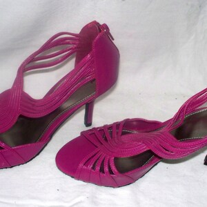 May include: A pair of bright pink high-heeled sandals with a strappy design.