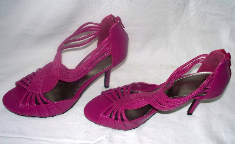 May include: A pair of bright pink high-heeled sandals with a strappy design.