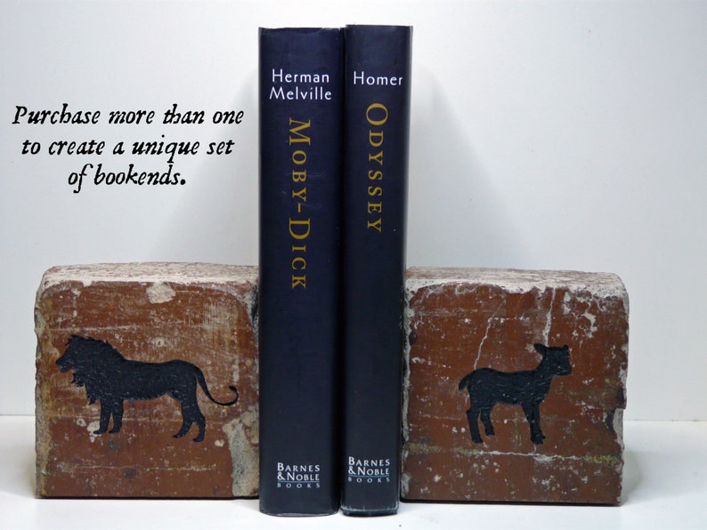 May include: Two bookends made from bricks, each with a black animal silhouette. One features a lion, the other a lamb. The bookends flank two navy blue books, "Moby-Dick" and "Odyssey."