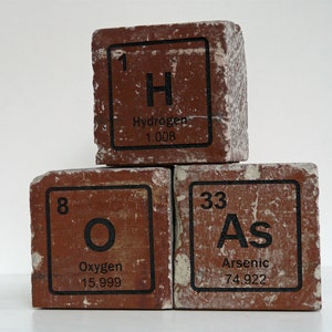 May include: Three stacked, reddish-brown, brick-like blocks with black text. The top block reads "1 H Hydrogen 1.008". The middle block reads "8 O Oxygen 15.999". The bottom block reads "33 As Arsenic 74.922".