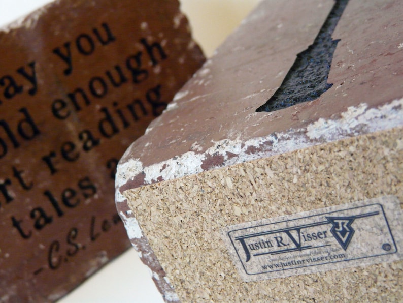 May include: Two rectangular, reddish-brown decorative blocks with white edges. One block features the quote "May you old enough reading short tales - C.S. Lewis" in black text. The other block has a cork base and a "Justin R. Visser" sticker.