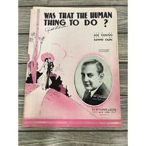 Op de afbeelding: Een vintage bladmuziekomslag getiteld Was That The Human Thing To Do? met een roze en zwarte illustratie van een koppel met een paraplu, een portret van Guy Lombardo en credits voor Joe Young en Sammy Fain, uitgegeven door M. Witmark & Sons.