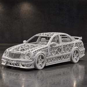 May include: A white scale model of a saloon car featuring an intricate, openwork filigree pattern across the entire body, including the bonnet, doors, and roof. The vehicle has a front grille, five-spoke wheels, and a rear spoiler, all in white.