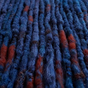 Könnte beinhalten: Blaue und orangefarbene synthetische Dreadlocks mit goldenen Perlen.
