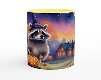 May include: A ceramic mug with a yellow interior and rim, featuring a printed illustration of a raccoon wearing a purple witch hat and holding a jack-o'-lantern pumpkin. The background depicts a house at twilight with autumn leaves.