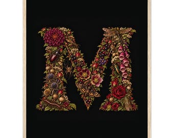 Op de afbeelding: Een ingelijste kunstdruk met de letter M, samengesteld uit complexe botanische elementen zoals donkerrode dahlia's, rozen en vingerhoedskruid, afgewisseld met diverse insecten zoals een libel, spin en mot op een zwarte achtergrond.