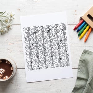 Puede incluir: Una hoja de papel rectangular blanca que presenta una ilustraci&oacute;n de arte lineal en blanco y negro de tallos de flores de dedalera verticales con hojas y peque&ntilde;as abejas dispersas por todo el patr&oacute;n floral, centrada en una superficie de madera blanca.