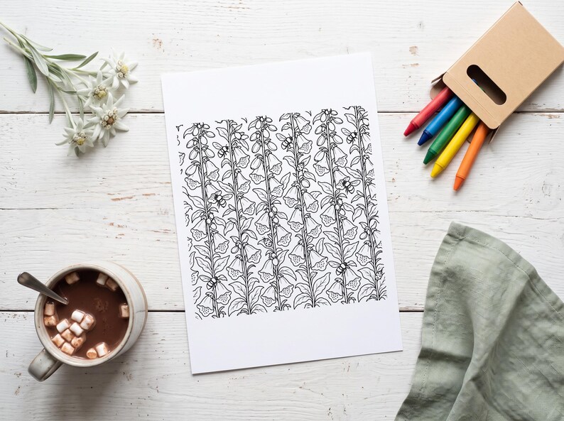Puede incluir: Una hoja de papel rectangular blanca que presenta una ilustraci&oacute;n de arte lineal en blanco y negro de tallos de flores de dedalera verticales con hojas y peque&ntilde;as abejas dispersas por todo el patr&oacute;n floral, centrada en una superficie de madera blanca.