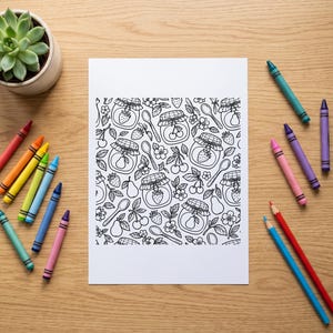 Op de afbeelding: Een wit rechthoekig vel papier met een zwart-wit lijnpatroon van jampotten, aardbeien, kersen, peren en lepels. Het papier is omringd door een verzameling kleurrijke waskrijtjes en een kleine groene vetplant.