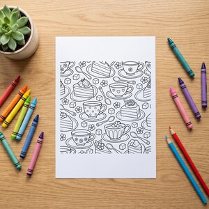 Op de afbeelding: Een wit rechthoekig kleurvel met een herhalend zwart-wit lijnpatroon van theekopjes, schoteltjes, stukjes taart, lepels, suikerklontjes en kleine bloemen, omringd door een assortiment kleurrijke waskrijtjes.