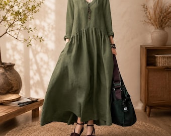Peut inclure: Une robe longue vert olive à manches longues avec un décolleté en V et une taille froncée. La robe présente une jupe ample et fluide, associée à un sac à bandoulière vert foncé et des sandales à lanières marron foncé. Un long collier à clé est porté.