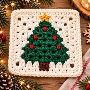 May include: A square crochet granny square featuring a cream-colored border and a central dark green Christmas tree motif. The tree is decorated with small red yarn knots and topped with a yellow star, with a brown yarn trunk at the base.