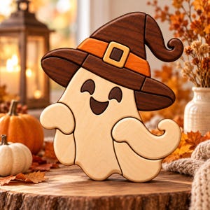 May include: A wooden puzzle shaped like a smiling ghost wearing a dark brown witch hat with an orange band and a light yellow buckle. The ghost figure is crafted from light-colored wood with dark brown accents for the eyes and mouth.