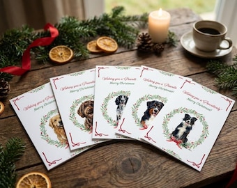 Puede incluir: Un conjunto de cinco tarjetas de felicitación navideñas rectangulares blancas con ilustraciones de diferentes razas de perros enmarcadas por coronas verdes. Cada tarjeta muestra el texto rojo Wishing you a Pawsitively Merry Christmas.