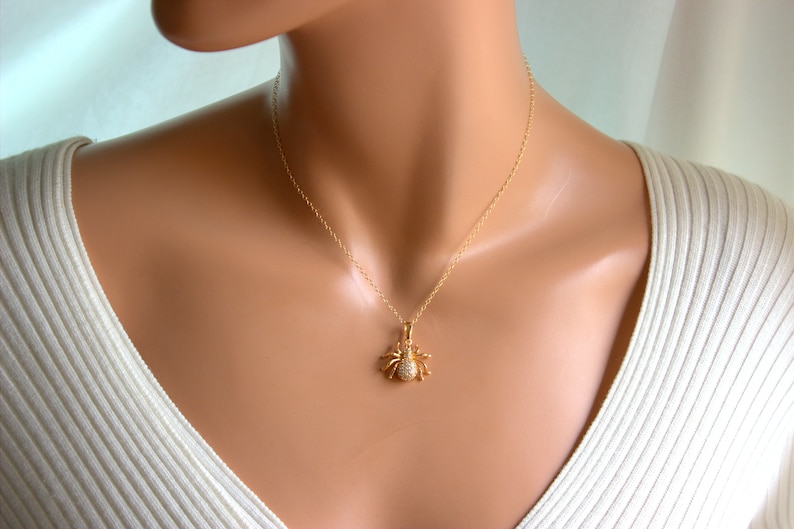 May include: A gold chain necklace with a small, sparkling spider pendant.