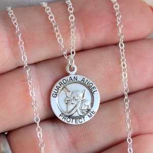 May include: Silver chain necklace with a round pendant featuring a guardian angel with the words "Guardian Angel Protect Me" around the edge.