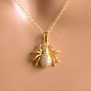 May include: A gold chain necklace with a sparkling spider pendant. The spider is made of gold and has clear rhinestones for eyes and body.