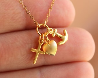 May include: Gold necklace with a heart, cross, and anchor charm. The charms are all connected to a delicate gold chain.