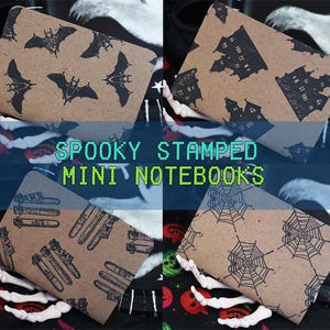 May include: Four mini notebooks with brown covers and black stamped designs. The designs include bats, haunted houses, test tubes, and spiderwebs. The text "SPOOKY STAMPED MINI NOTEBOOKS" is displayed in the center.