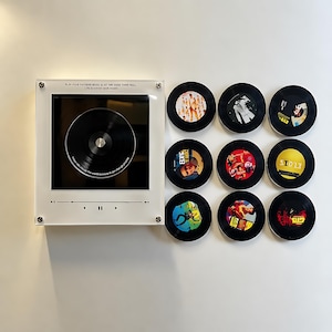 May include: A square white acrylic wall display featuring a central black vinyl record and music player interface graphics with the text "PLAY YOUR FAVOURITE MUSIC & LET THE GOOD TIMES ROLL. Life is better with music." Nine circular vinyl records are arranged to the right.