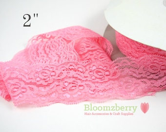 May include: Pink lace ribbon, 2 inches wide, with a floral pattern. The ribbon is partially unrolled from a white spool. The Bloomzberry logo is visible in the bottom right corner.