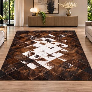 May include: A rectangular area rug featuring a patchwork design of cowhide squares in shades of brown, tan, and white. The pattern consists of dark brown outer edges transitioning into a central diamond-shaped cluster of white and brown patches.