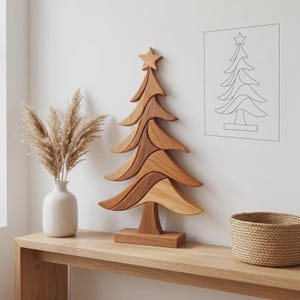 Puede incluir: Una escultura de árbol de Navidad de madera compuesta por segmentos curvos apilados en tonos marrón claro y medio, rematada con una estrella. El árbol se asienta sobre una base rectangular, con un acabado liso y vetas de madera natural.