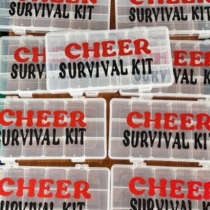 May include: Six clear plastic storage boxes with red and black glitter lettering that reads "CHEER SURVIVAL KIT".