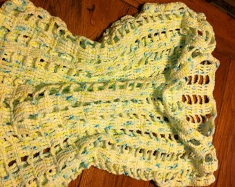 May include: A white crochet shawl with blue and yellow accents. The shawl has a lacy pattern and is made with a soft yarn.