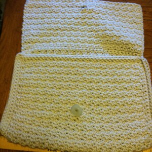 May include: A beige crocheted clutch bag with a single button closure.