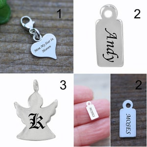 May include: Four silver charm pendants. The first is a heart-shaped pendant with the text "Mom My Star In Heaven". The second is a rectangular pendant with the name "Andy" engraved on it. The third is an angel-shaped pendant with the letter "K" engraved on it. The fourth is a rectangular pendant with the name "Moses" engraved on it.